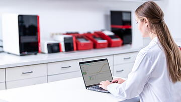 Lab assistant on desk in lab with computer