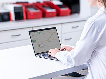 Lab assistant on desk in lab with computer